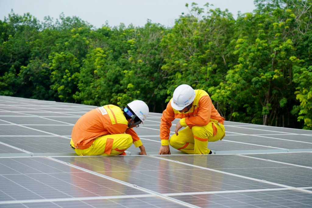 Arbeiter installieren an einem sonnigen Tag Photovoltaik-Solarmodule und fördern so erneuerbare Energien.