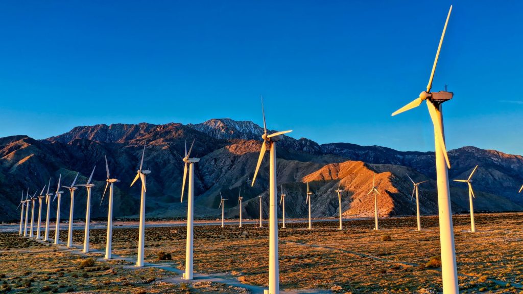 ein Haufen Windmühlen auf einem Feld mit Bergen im Hintergrund