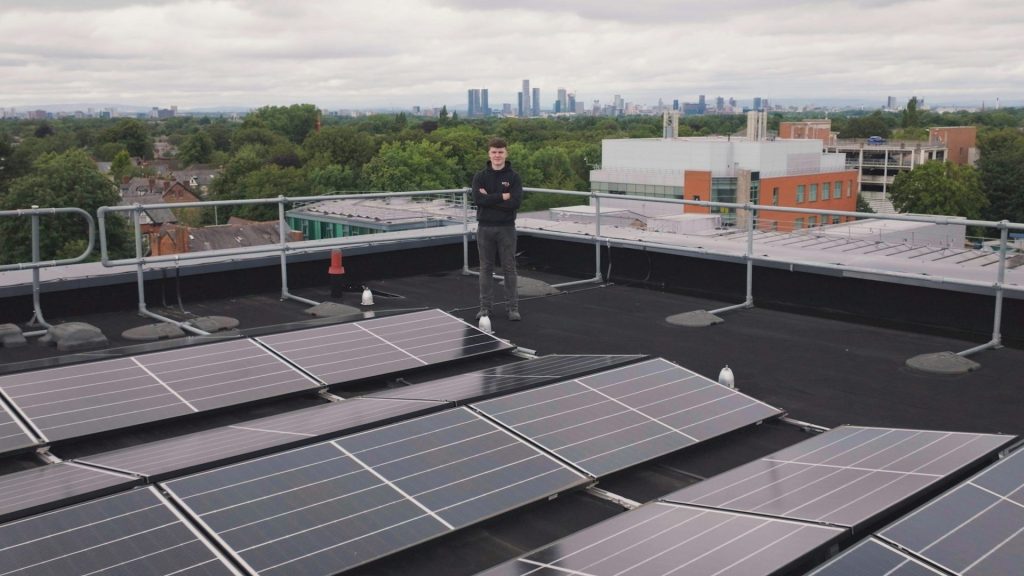 Ein Mann steht auf einem Dach neben Solarmodulen